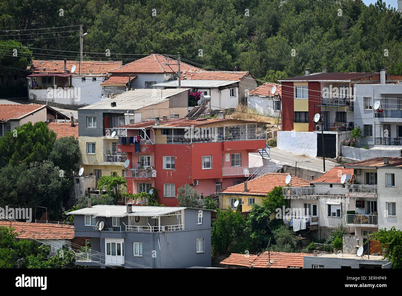 Quartiere residenziale denso con tetti di tegole rosse, balconi, parabole satellitari e alberi - paesaggio urbano telefotografico di vecchi condomini. Foto Stock