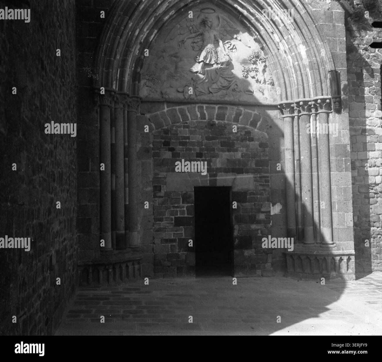 Una fotografia monocromatica di Henri Ferrand del 1890 registra la grande porta di Mont-Saint-Michel in Normandia. L'immagine architettonica documenta l'ingresso fortificato al complesso dell'abbazia e la sua struttura difensiva medievale. Foto Stock