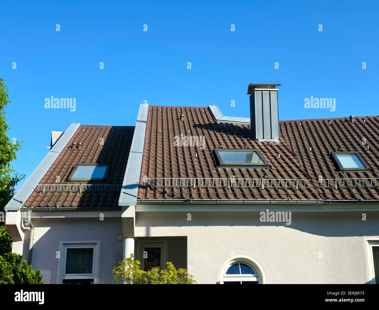affascinante tetto di casa tradizionale in condizioni eccellenti sotto un brillante cielo blu che mostra un fascino residenziale senza tempo Foto Stock