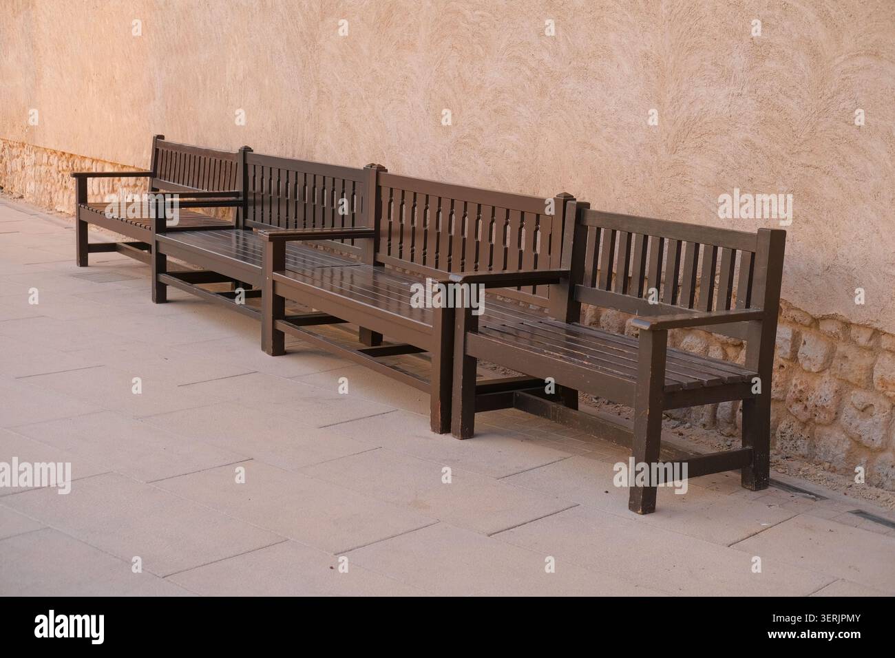 Panchine modulari in legno scuro nello spazio pubblico pedonale. Arredi urbani, posti a sedere pubblici. Foto Stock