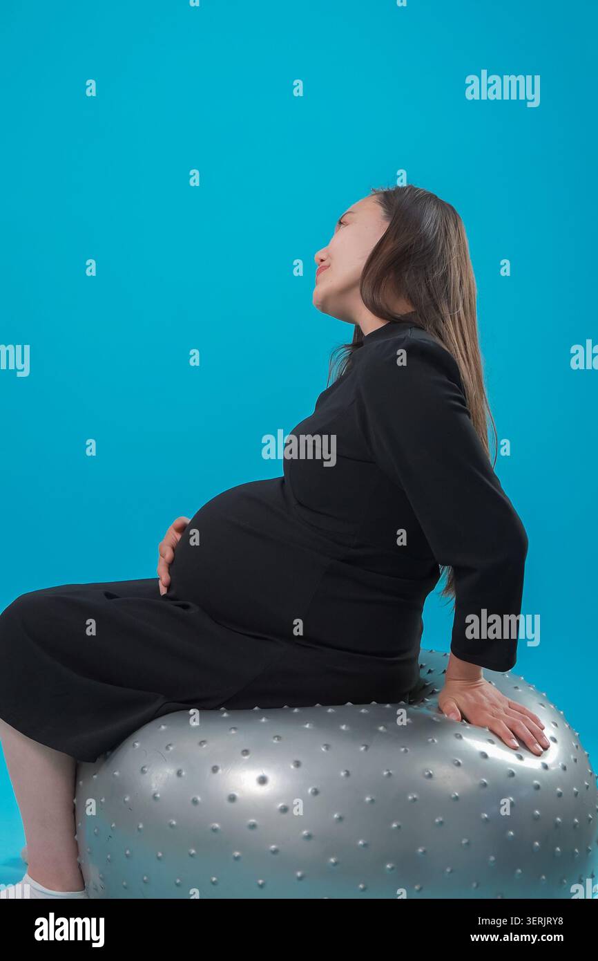Donna incinta seduta su un ballo di fitness in studio Foto Stock