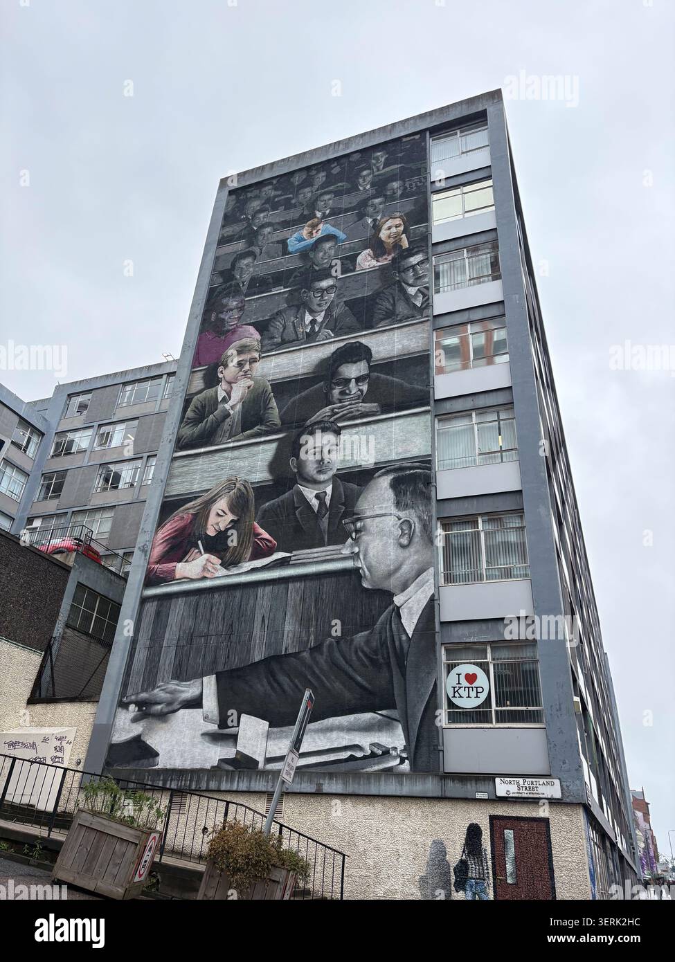 Un massiccio murale monocromatico di una scena di sala conferenze dipinta sul lato di un alto condominio urbano. Foto Stock