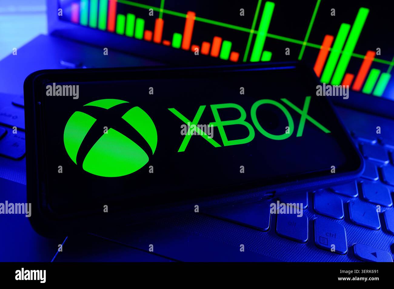 Logo Xbox su telefono cellulare con grafico delle prestazioni del mercato azionario sullo schermo del computer Foto Stock