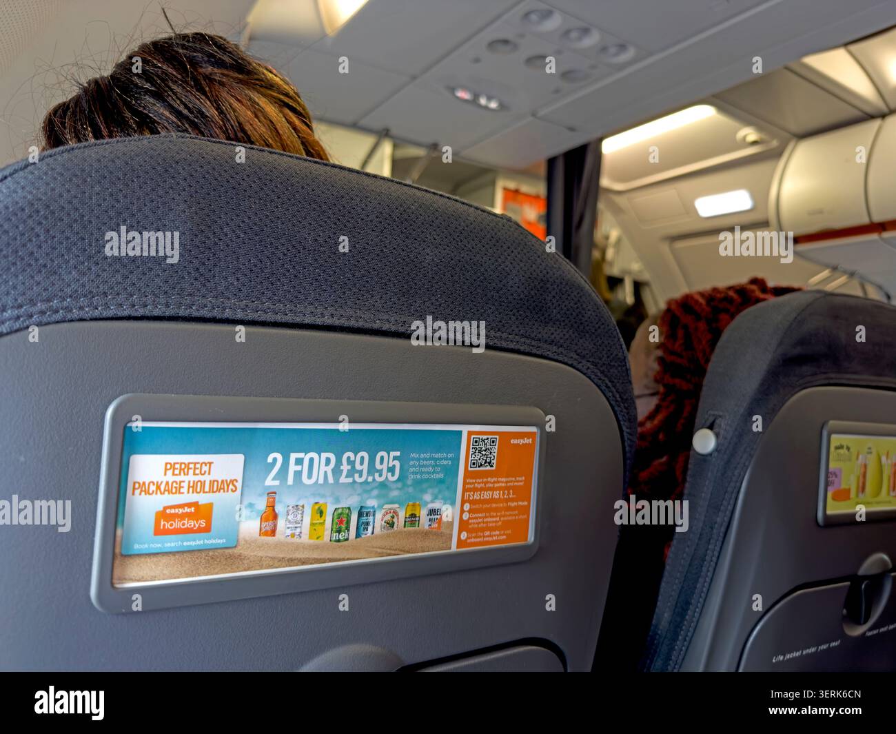 Pubblicità sullo schienale del sedile per bevande e vacanze tutto compreso di easyJet all'interno della cabina di un volo di linea a basso costo da un aeroporto regionale. Foto Stock