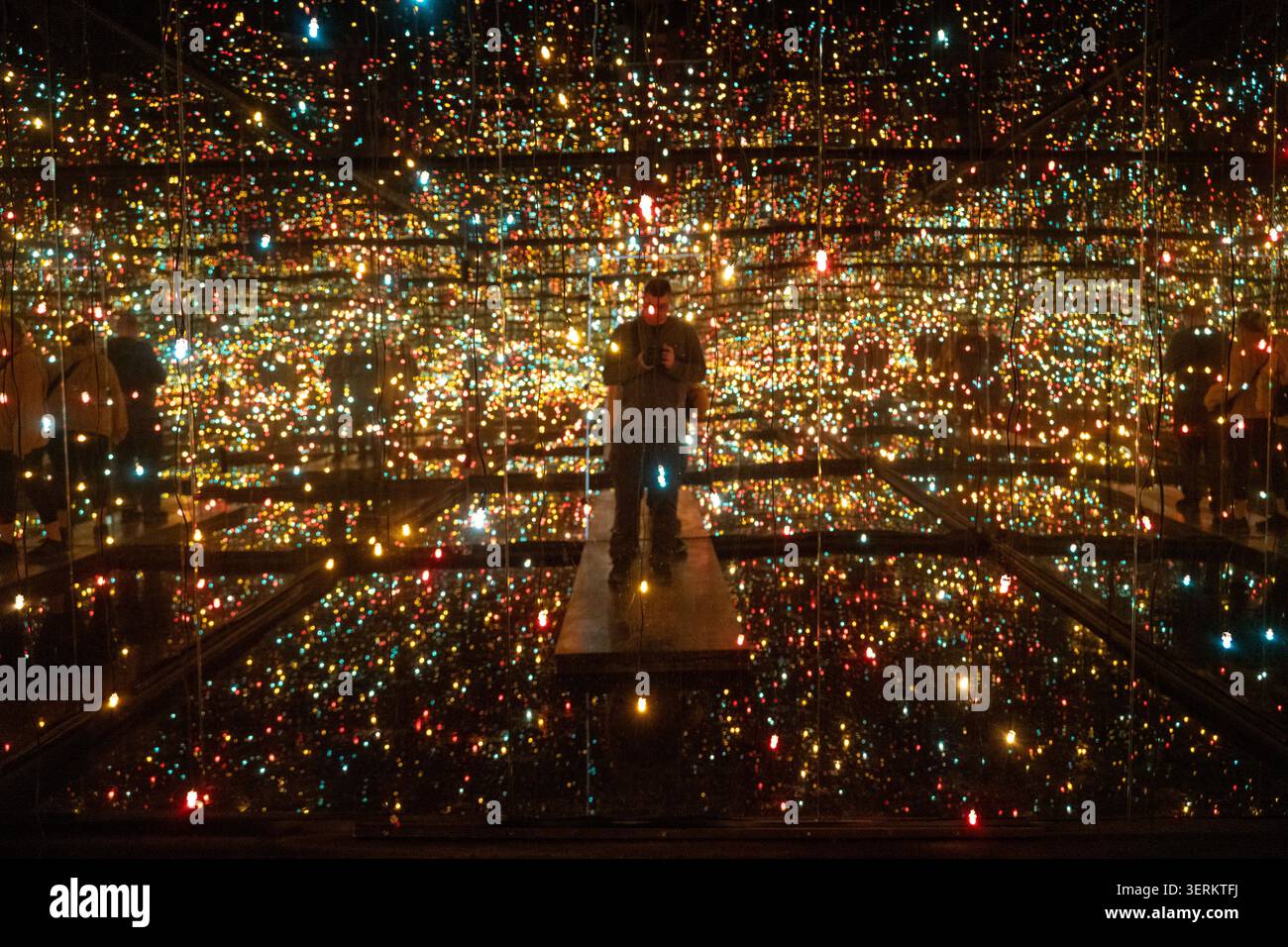 Nancy, Francia - 9 marzo 25: Fotografia di un'installazione di luci a specchio a sfioro immersiva con punti di luce multicolori e un visitatore riflesso in m Foto Stock
