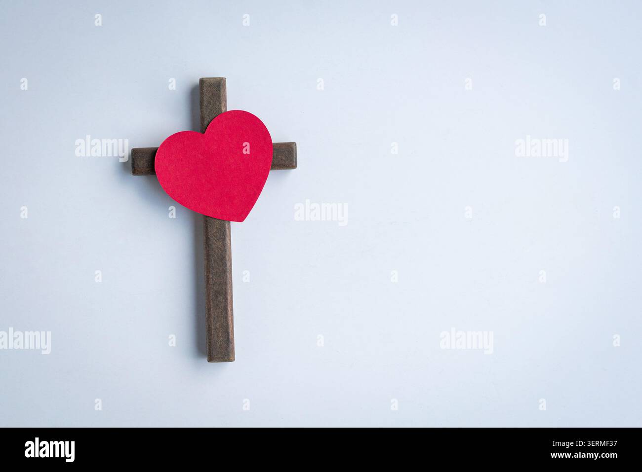 Cuore di carta rossa sulla cima del crocifisso a croce di legno. Isolato su sfondo bianco. Foto Stock