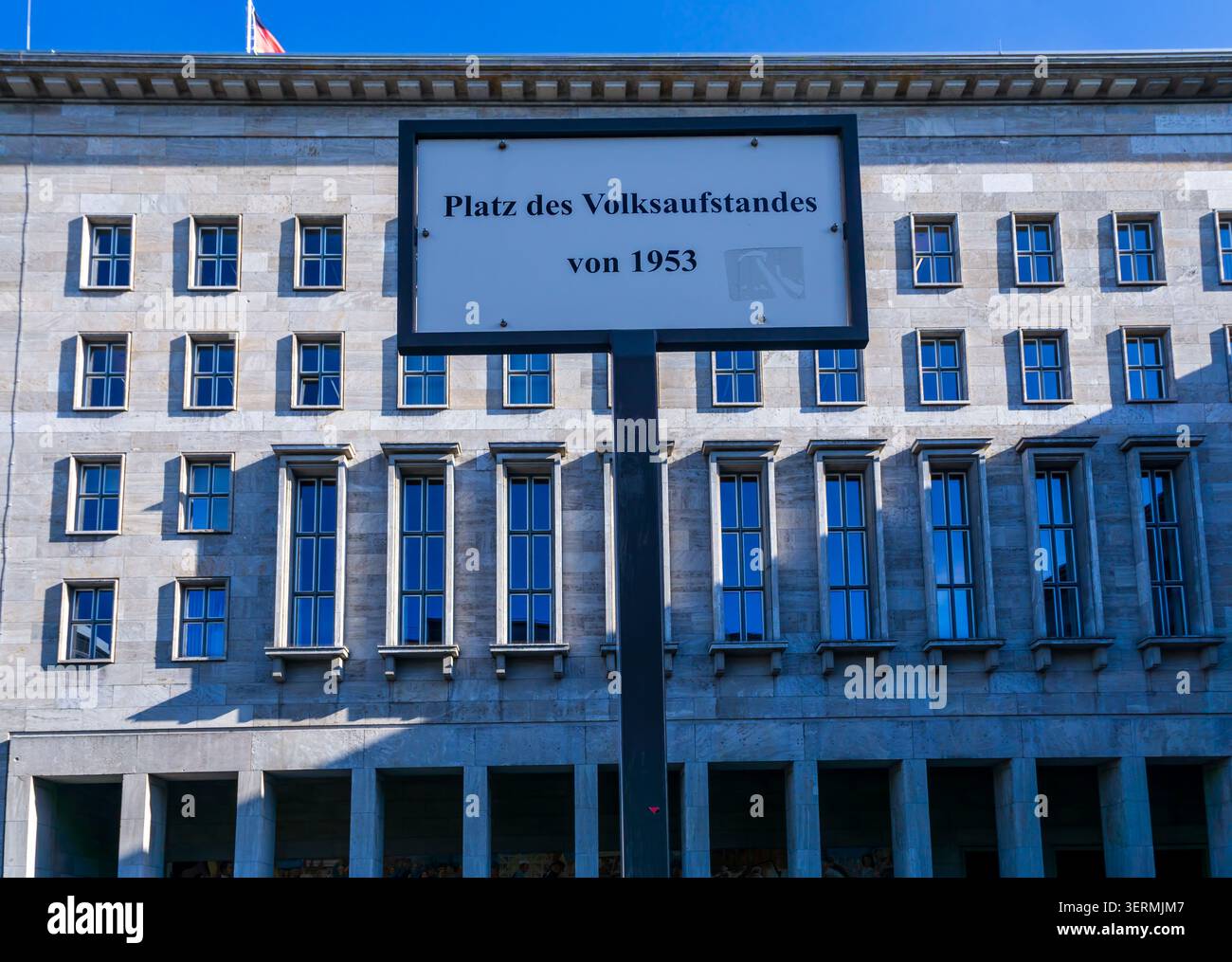 Cartello stradale Platz des Volksaufstandes von 1953 con lo storico edificio del Ministero federale delle Finanze a Berlino, Germania. Piazza della rivolta dei popoli. Foto Stock