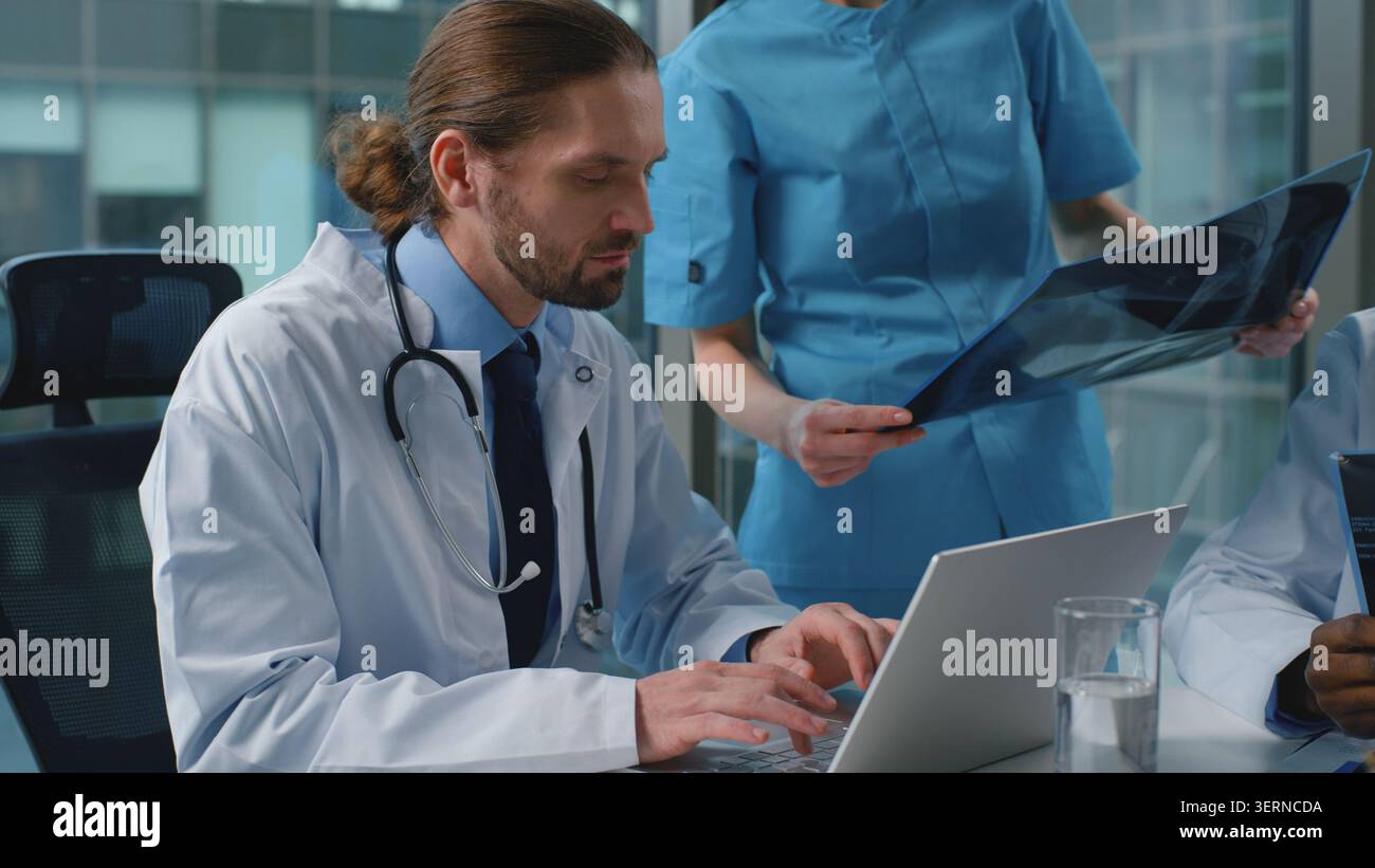 Diversità multirazziale team medico di medici che discutono radiografie lavorare con laptop parlare alla conferenza di medicina. Tre medici chirurghi Foto Stock