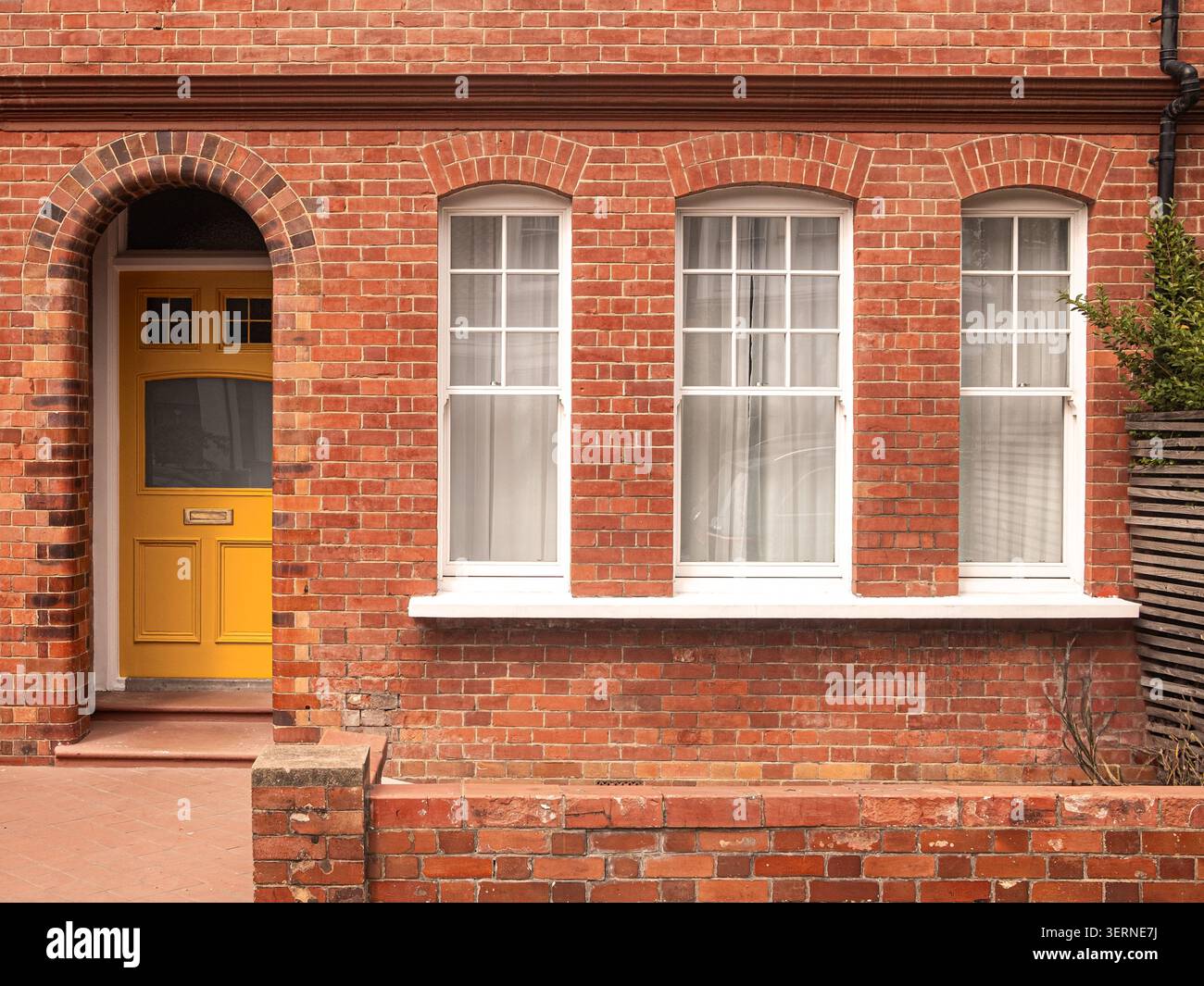 LONDRA - casa in mattoni rossi con porta d'ingresso gialla e finestre bianche Foto Stock