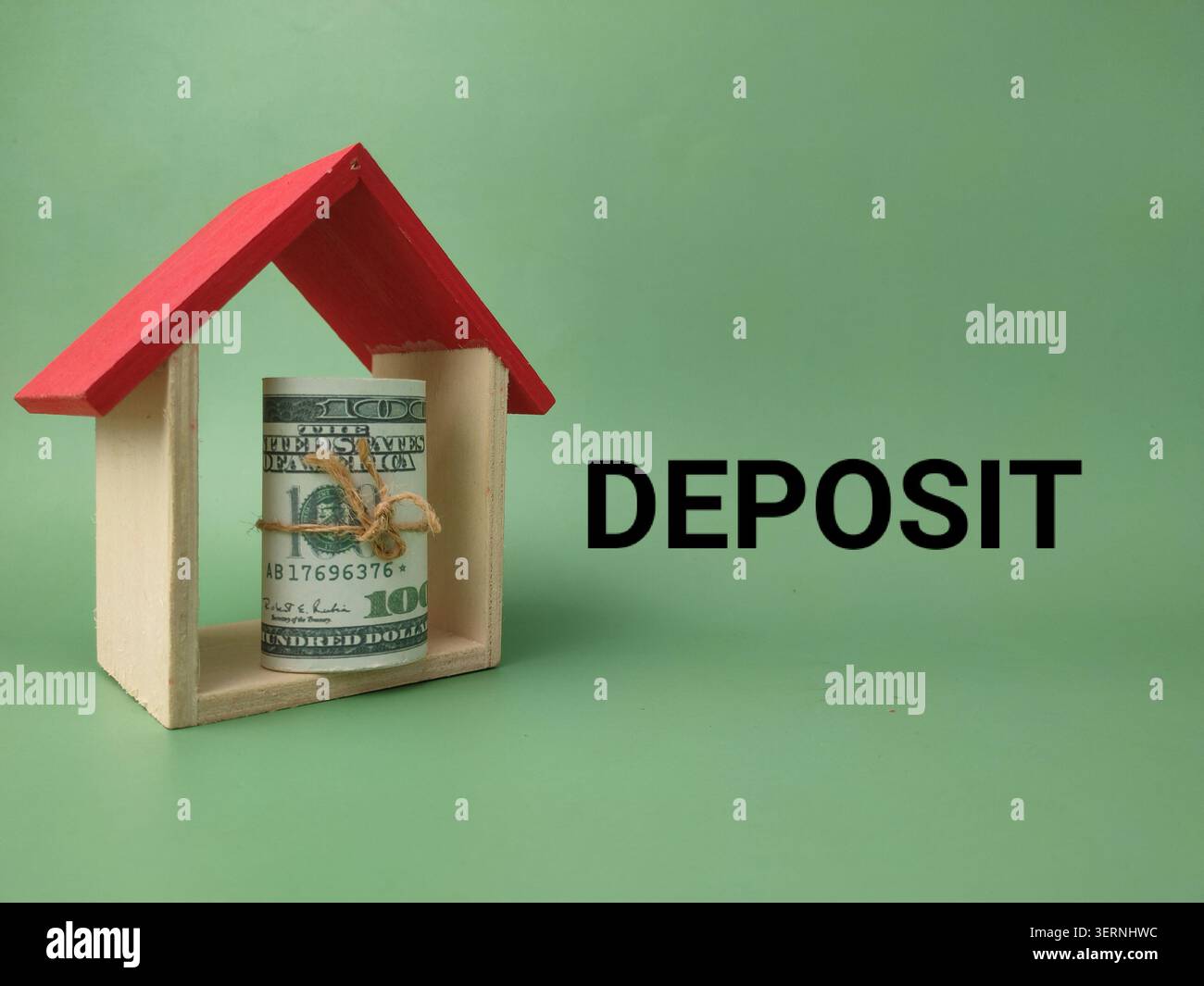 Un pacchetto di dollari arrotolato si trova all'interno di una cornice in legno in miniatura accanto al DEPOSITO DI testo in grassetto sul verde. Foto Stock