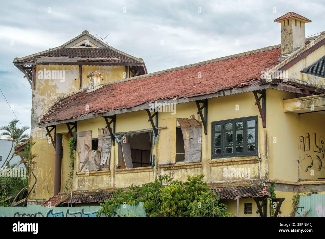 Vecchio edificio coloniale abbandonato con vernice gialla sbucciante e un tetto danneggiato Foto Stock