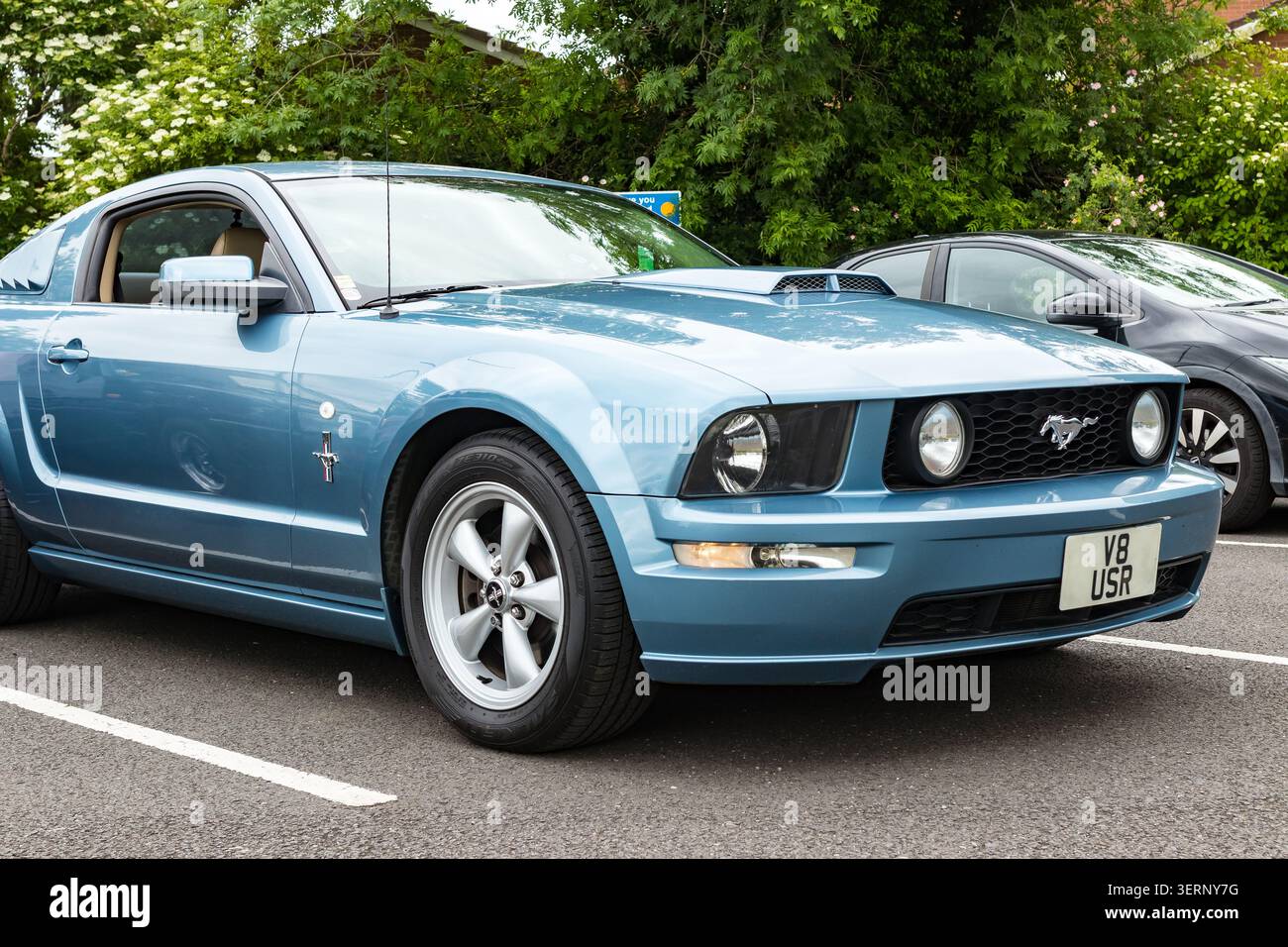 Blue ford mustang gt coupé parcheggiata in un parcheggio nel regno unito con altre auto e alberi sullo sfondo Foto Stock