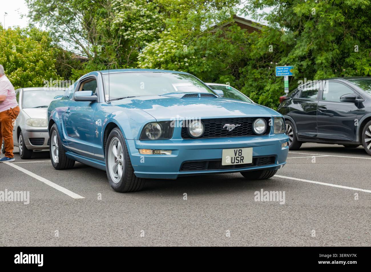 Blue ford mustang gt coupé parcheggiata in un parcheggio nel regno unito con altre auto e alberi sullo sfondo Foto Stock