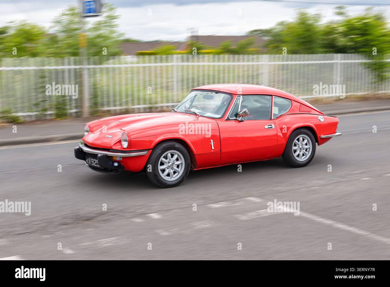 Red Triumph GT6 Mk III guida di un'auto sportiva classica e in movimento su una strada del Regno Unito Foto Stock
