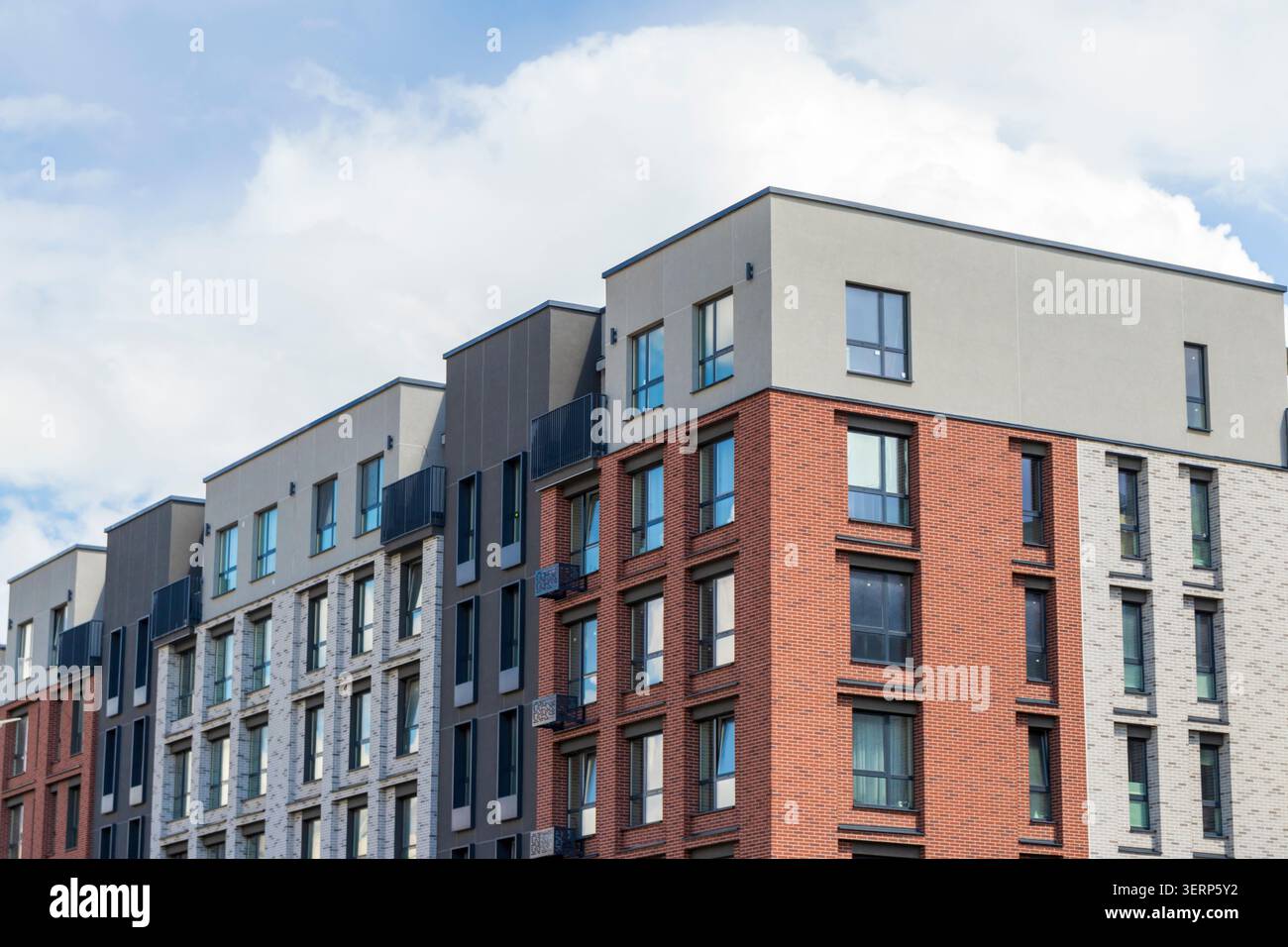 Moderna facciata residenziale con mattoni rossi e pannelli di rivestimento grigi Foto Stock