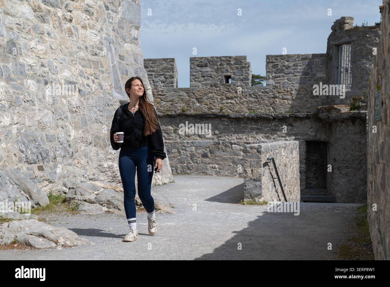 Donna che cammina attraverso le antiche mura del castello esplorando la storia Foto Stock