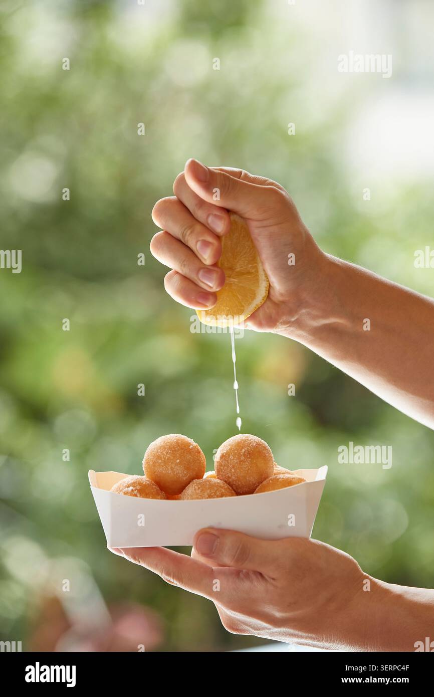 Ciambelle di riso dolce coreano fritte dorate accatastate in una ciotola di metallo e su un vassoio, primo piano fotografia di cibo su uno sfondo caldo Foto Stock