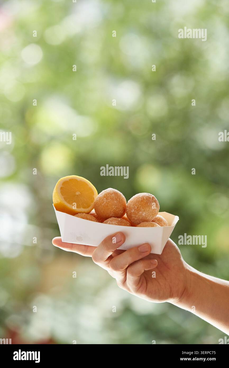 Ciambelle di riso dolce coreano fritte dorate accatastate in una ciotola di metallo e su un vassoio, primo piano fotografia di cibo su uno sfondo caldo Foto Stock