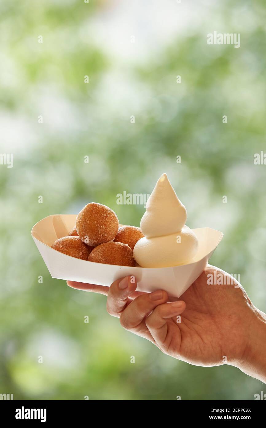 Ciambelle di riso dolce coreano fritte dorate accatastate in una ciotola di metallo e su un vassoio, primo piano fotografia di cibo su uno sfondo caldo Foto Stock