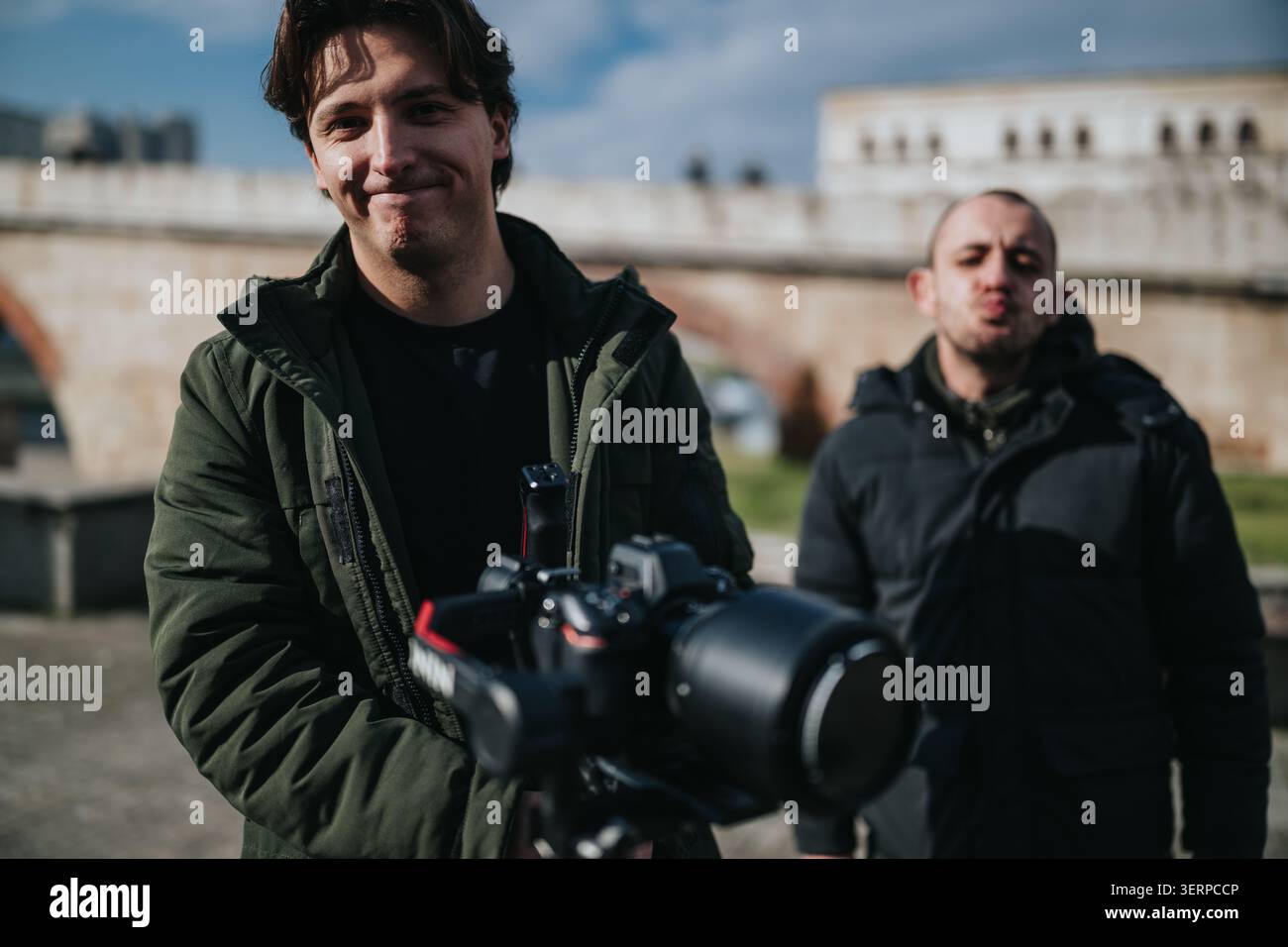 Due fotografi a una riunione d'affari invernale all'aperto con una macchina fotografica professionale vicino a un ponte di pietra Foto Stock