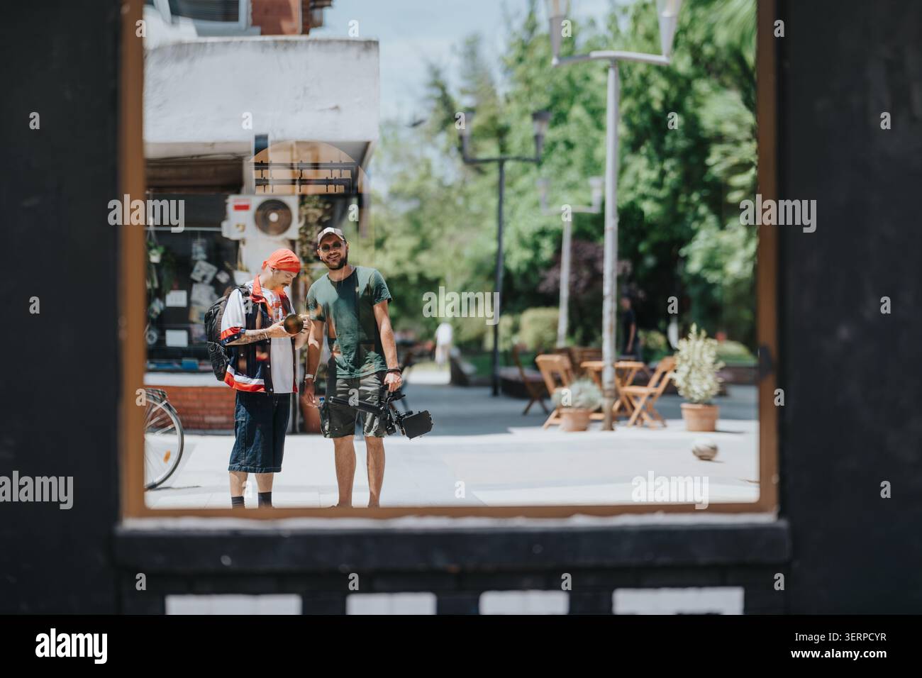 Due studenti delle scuole superiori con macchina fotografica e zaino riflessi in una piazza soleggiata Foto Stock