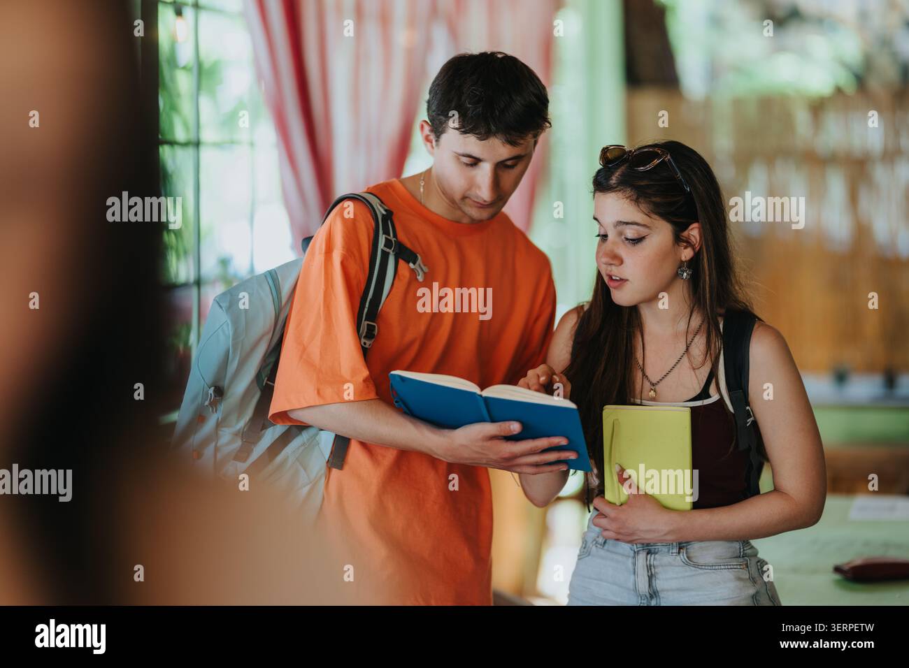 Studenti delle scuole superiori che studiano insieme a zaini e libri in un ambiente scolastico informale Foto Stock