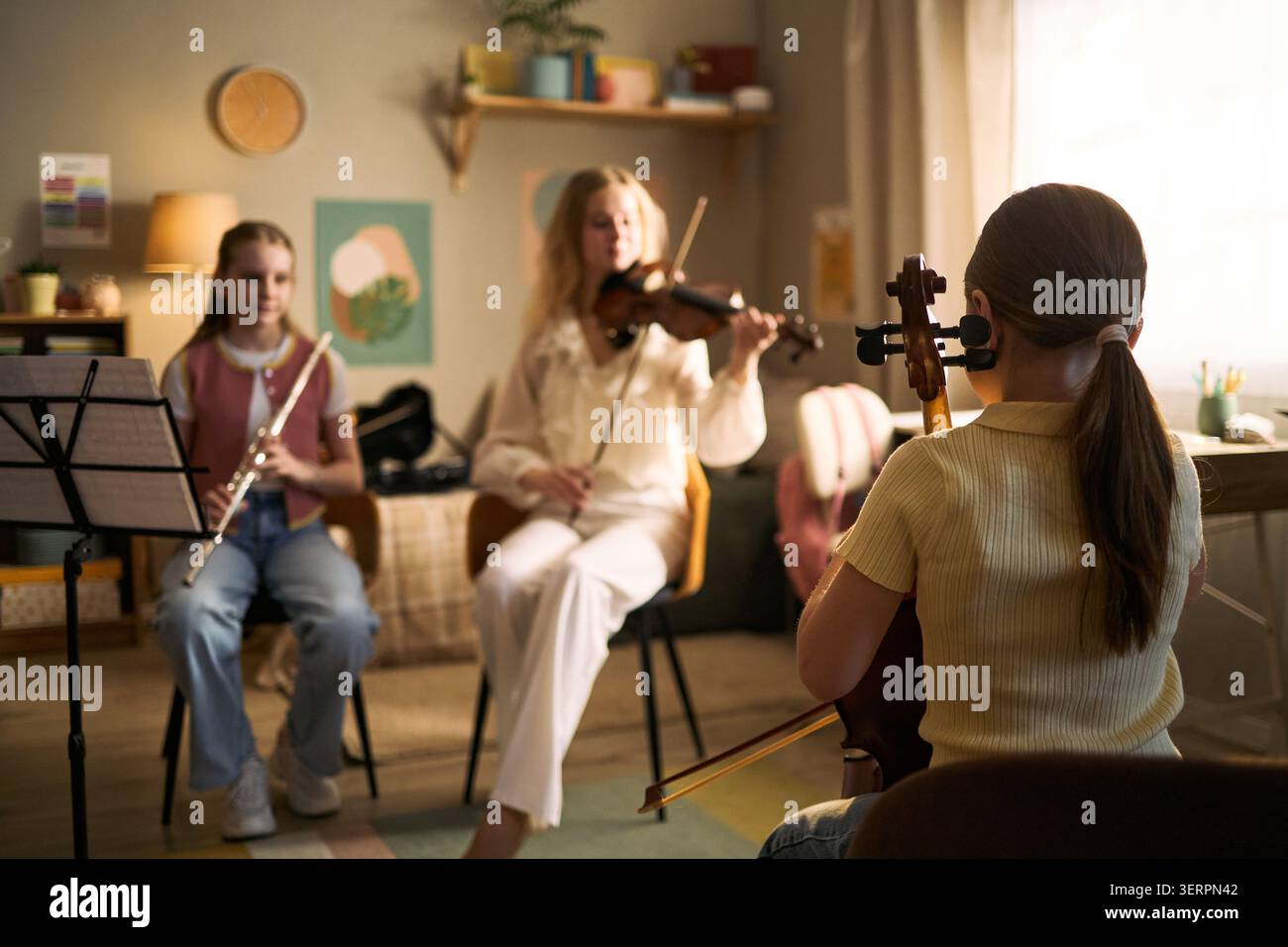 I bambini studiano musica e suonano violino flauto e violoncello durante la lezione, sviluppando creatività e lavoro di squadra. Ideale per educazione musicale, programmi artistici, campagne di apprendimento infantile Foto Stock
