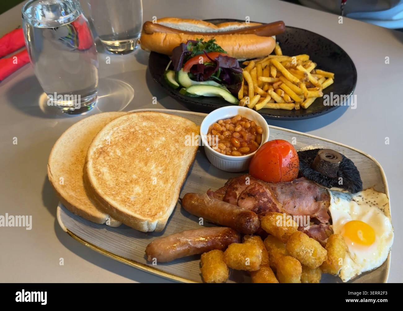 Colazione all'inglese completa e hot dog con patatine fritte: Abbondante pasto al brunch da caffetteria, sfondo commerciale Foto Stock