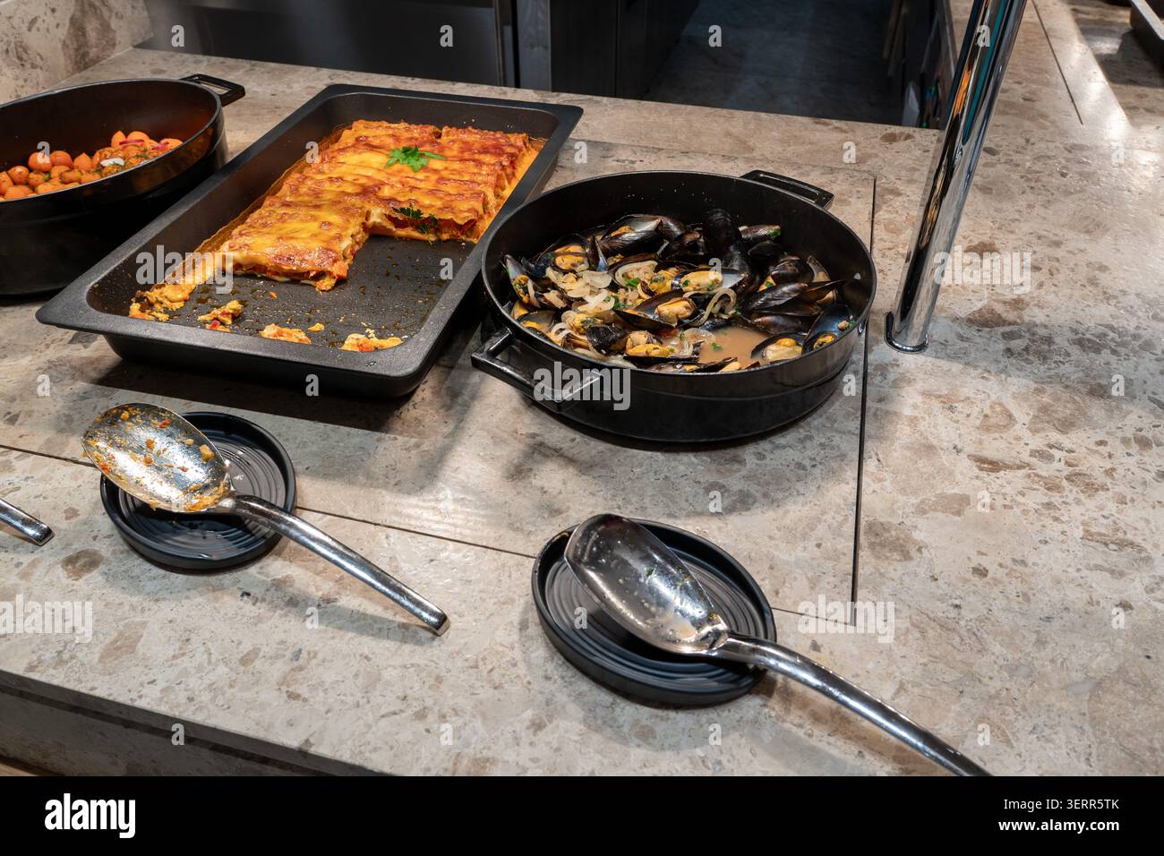 Una selezione di piatti gourmet caldi presso il buffet del ristorante dell'hotel, con cozze cotte al momento in salsa e un vassoio di lasagne al forno Il self-service foo Foto Stock