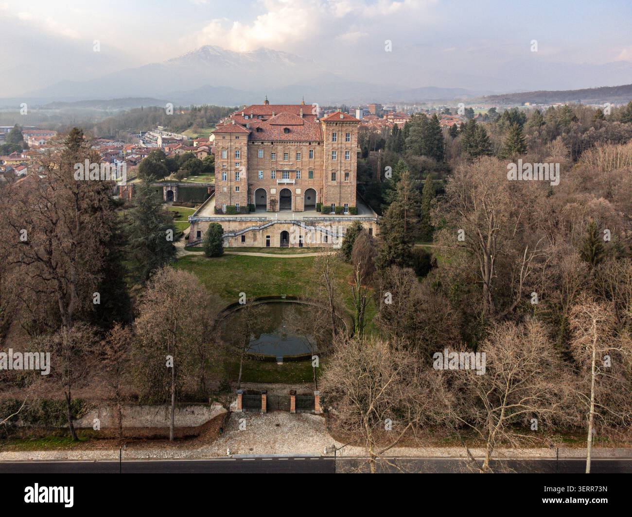 Veduta aerea del Castello Duca delle Aglie con la sua storica facciata in mattoni, i giardini formali e la fontana circolare sotto un cielo morbido ad Aglie, Piemonte, Italia. Foto Stock