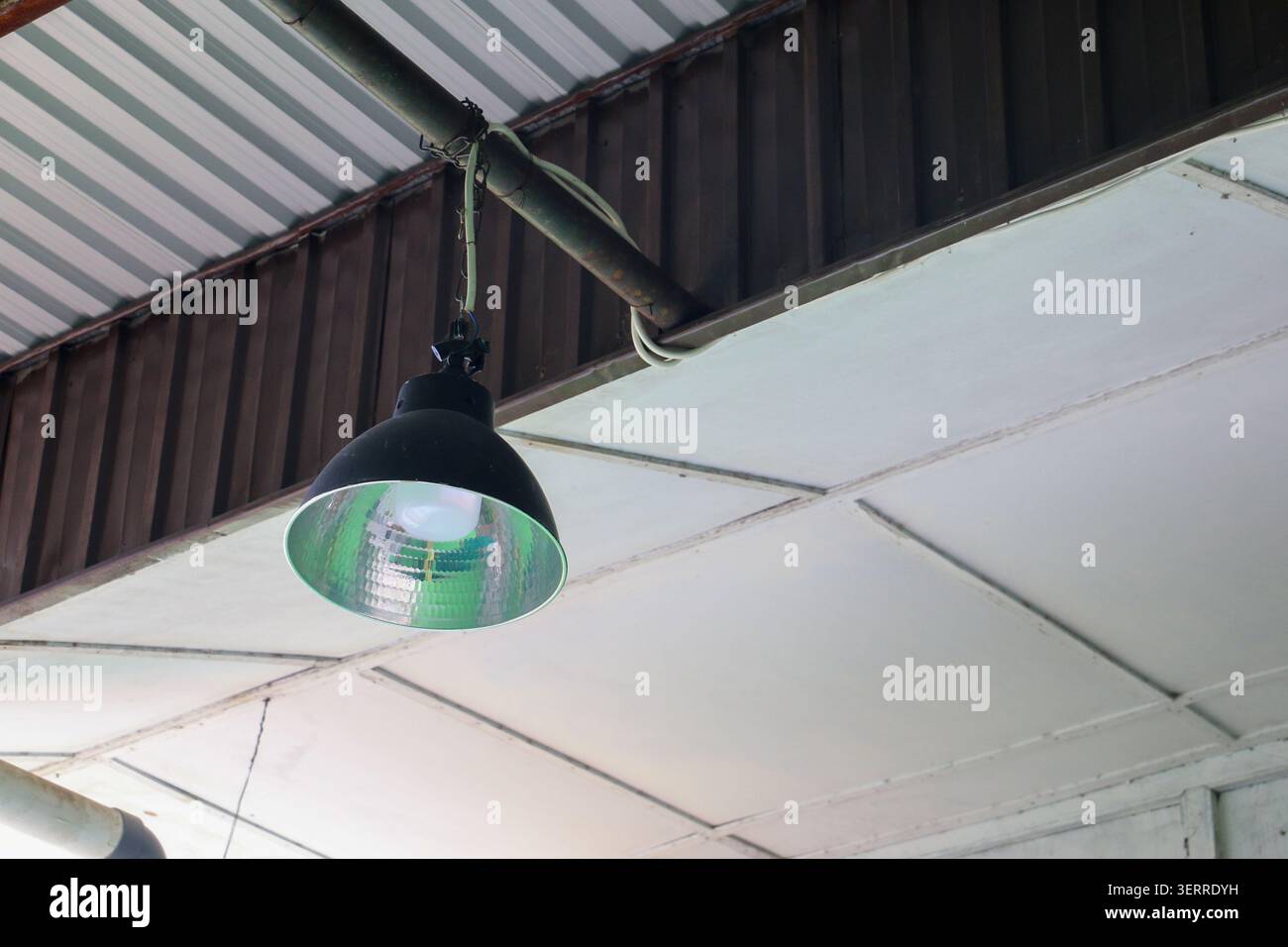 Lampada a LED sospesa industriale sotto il soffitto del tetto in metallo con cablaggio elettrico, concetto di moderno impianto di illuminazione per magazzini e officine Foto Stock