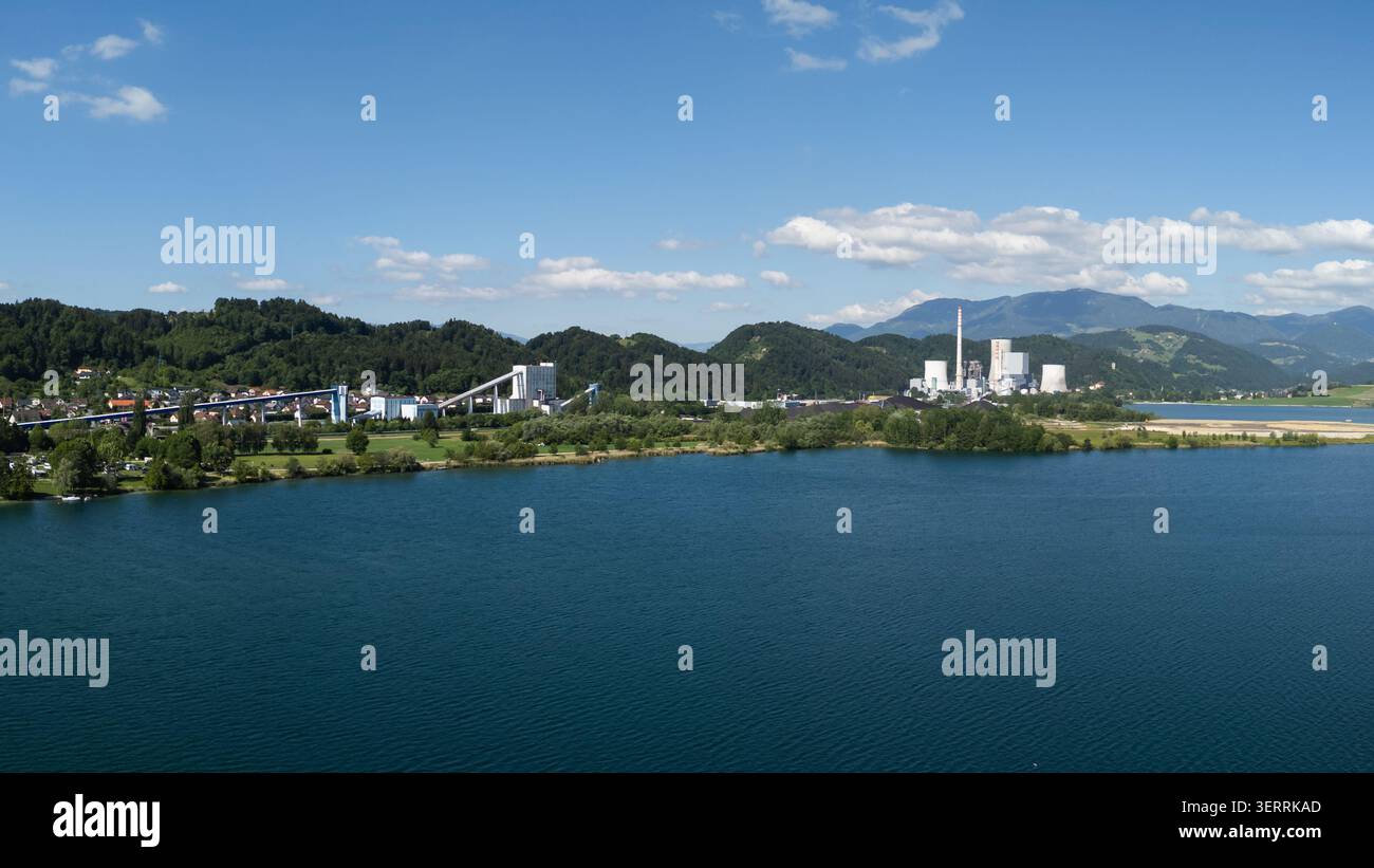La centrale termica produce elettricità vicino a un lago circondato da montagne e infrastrutture industriali per la produzione di energia. Foto Stock