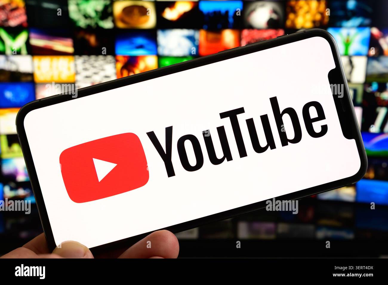 Parigi, Francia - 19 giugno 2026: Una persona possiede uno smartphone che mostra il logo YouTube con uno sfondo digitale. Foto Stock
