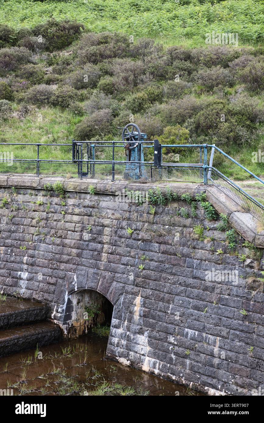 Un meccanismo di distribuzione in ghisa d'epoca sulla struttura della diga in muratura gritstone sopra un condotto d'acqua ad arco a Yeoman Hey Reservoir, Regno Unito. Foto Stock