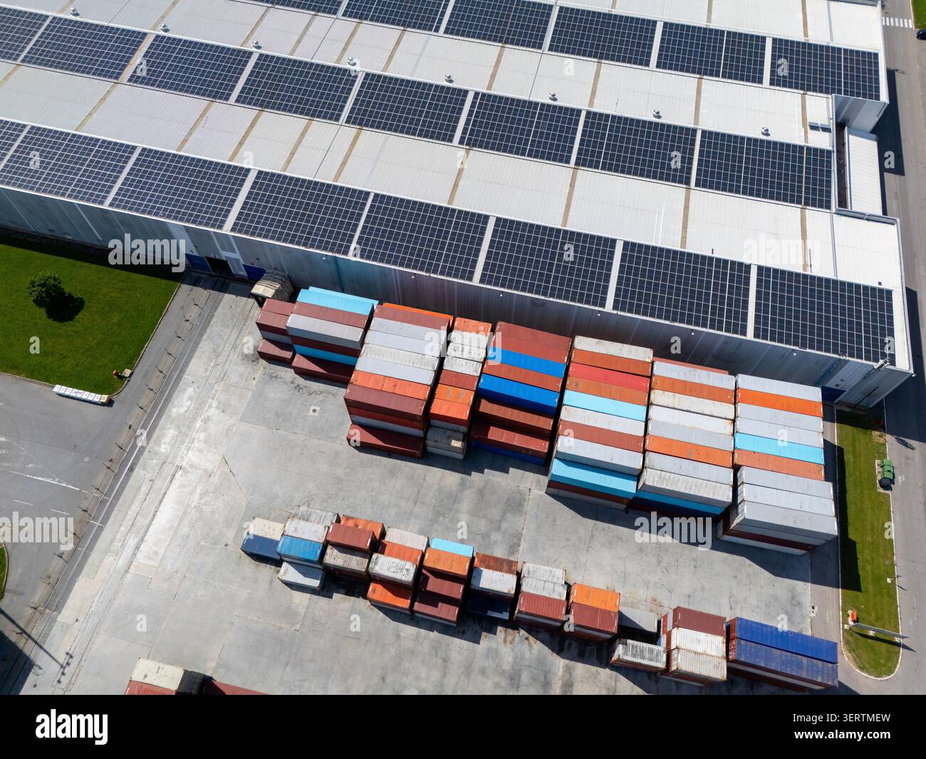 Vista dall'alto aerea di un hub logistico verde con pannelli solari e contenitori per spedizioni Foto Stock