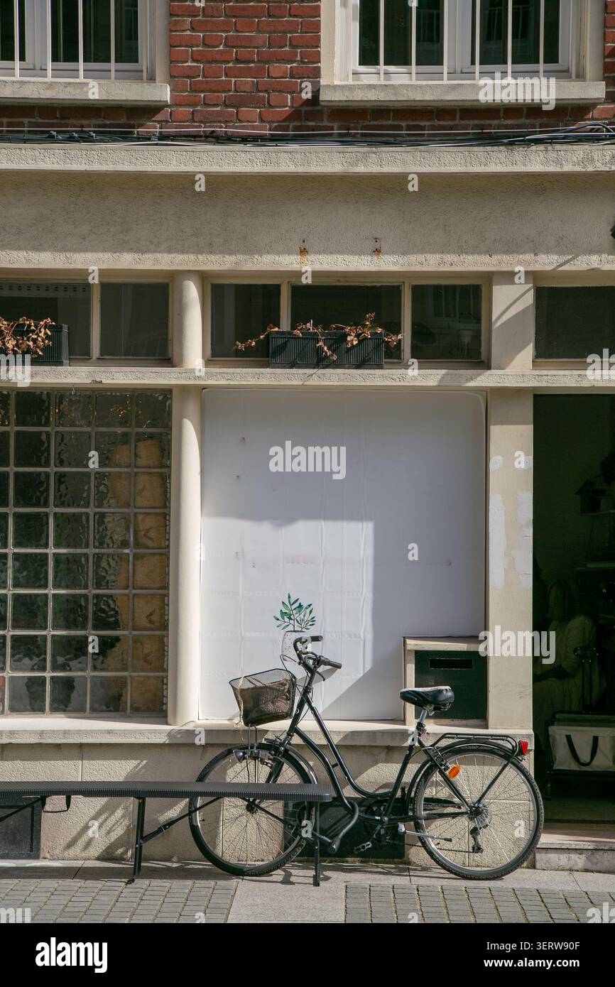 Classica bicicletta da città nera verticale con cestello anteriore in filo metallico parcheggiato all'esterno di un negozio. La bicicletta è caratterizzata da un telaio passante Foto Stock