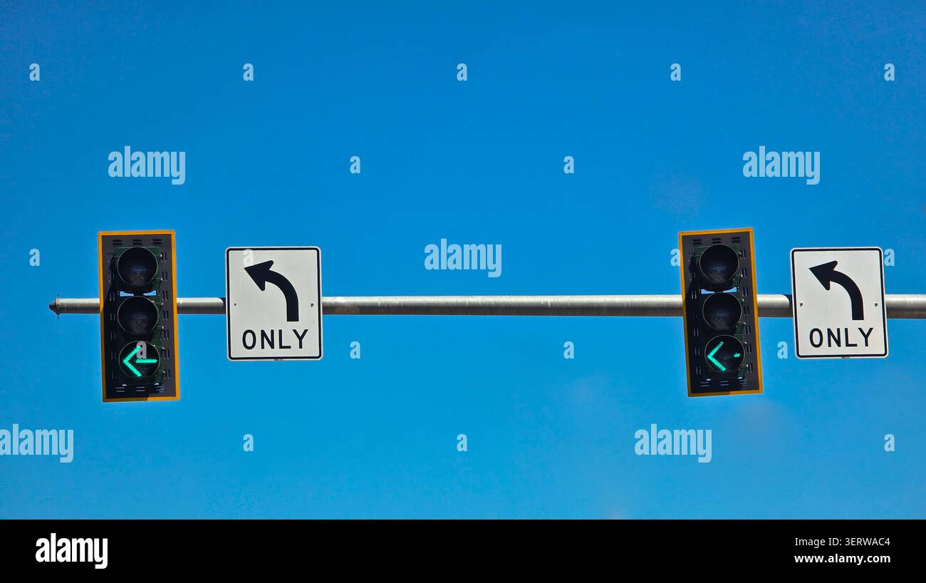 Doppio indicatore di direzione verde a sinistra con segnaletica orizzontale e Blue Sky Foto Stock