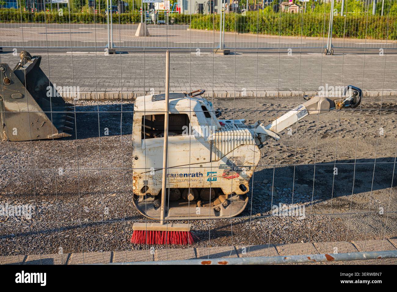 Kaarst, Germania, 10.06.2026 - rullo compattatore in cantiere dietro una recinzione metallica, un compattatore a piastra vibrante o una macchina a rulli per scavi parcheggiata Foto Stock