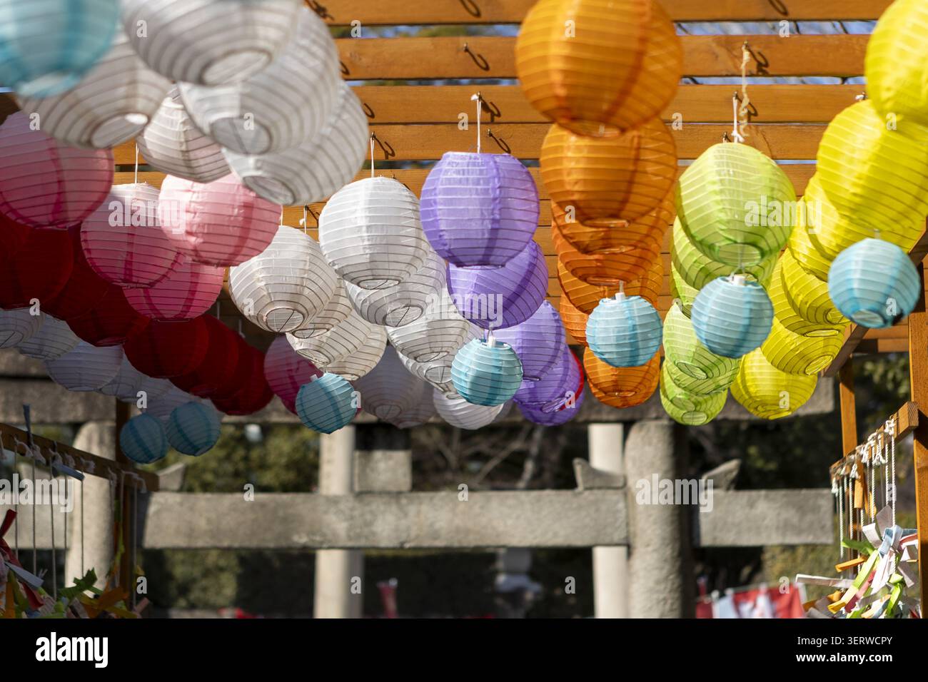 Vista delle colorate lanterne di carta appese da una struttura in legno in un tradizionale santuario di Osaka, Osaka, Giappone. Foto Stock