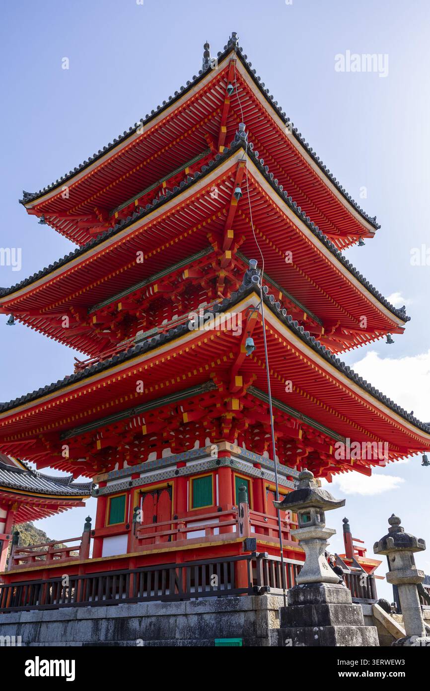 Vista dell'iconica pagoda rossa a tre piani al tempio Kiyomizu-dera con tradizionali lanterne di pietra sotto un cielo azzurro a Kyoto, Kyoto, Giappone. Foto Stock