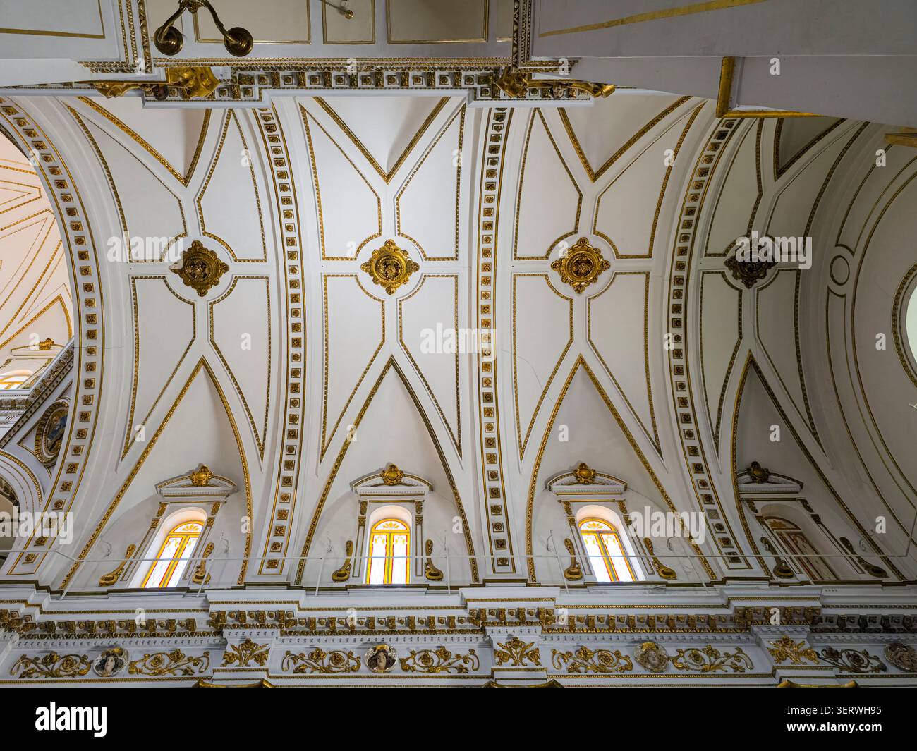 La scenografia mostra una vista simmetrica di un soffitto a volta. Cornici geometriche dorate e modanature ornamentali decorano il soffitto. Una fila di finestre ad arco è Foto Stock