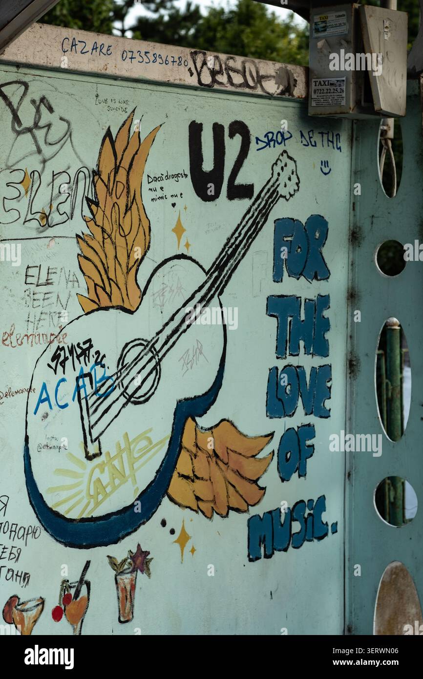 Si tratta di un primo piano di una cassetta in metallo blu chiaro ricoperta da graffiti colorati. La grafica principale presenta una chitarra acustica bianca con ali dorate Foto Stock
