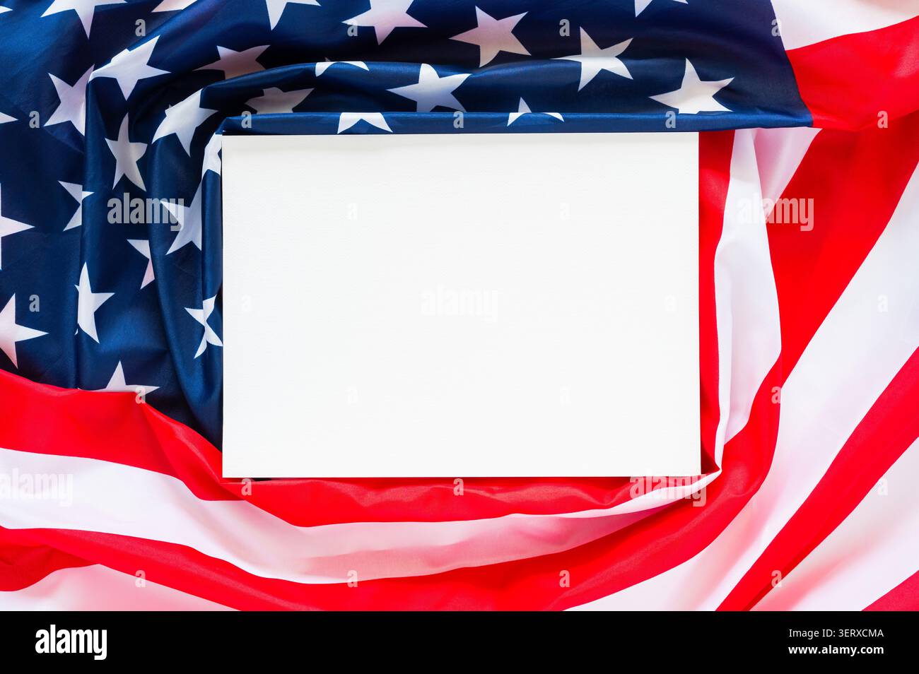 Una carta bianca bianca appoggiata su una bandiera americana drappeggiata, che funge da sfondo versatile per commemorare i 250 anni di indipendenza americana. Foto Stock