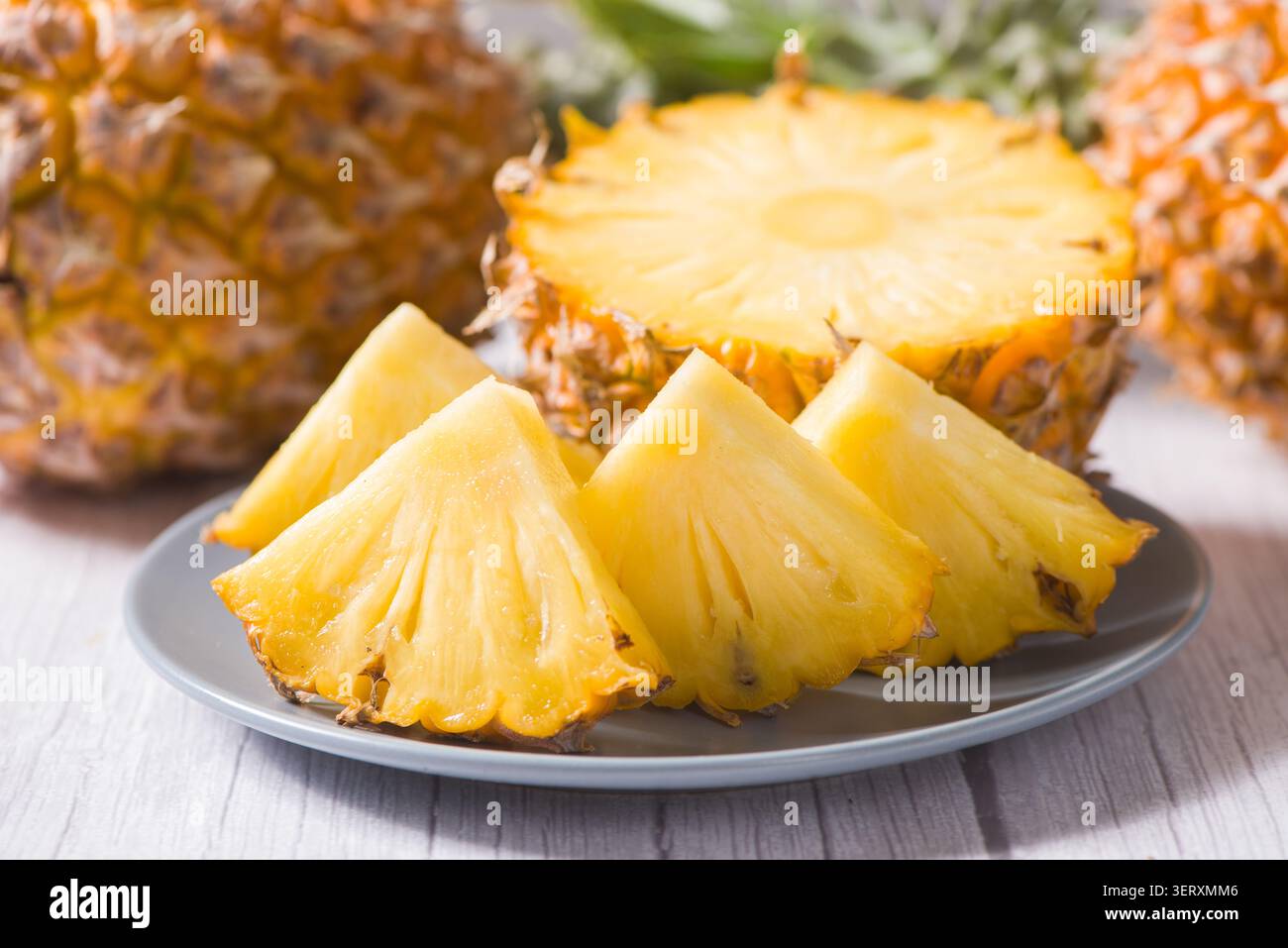 Le fette di ananas sono disposte su un piatto bianco con lo sfondo intero e metà di ananas Foto Stock