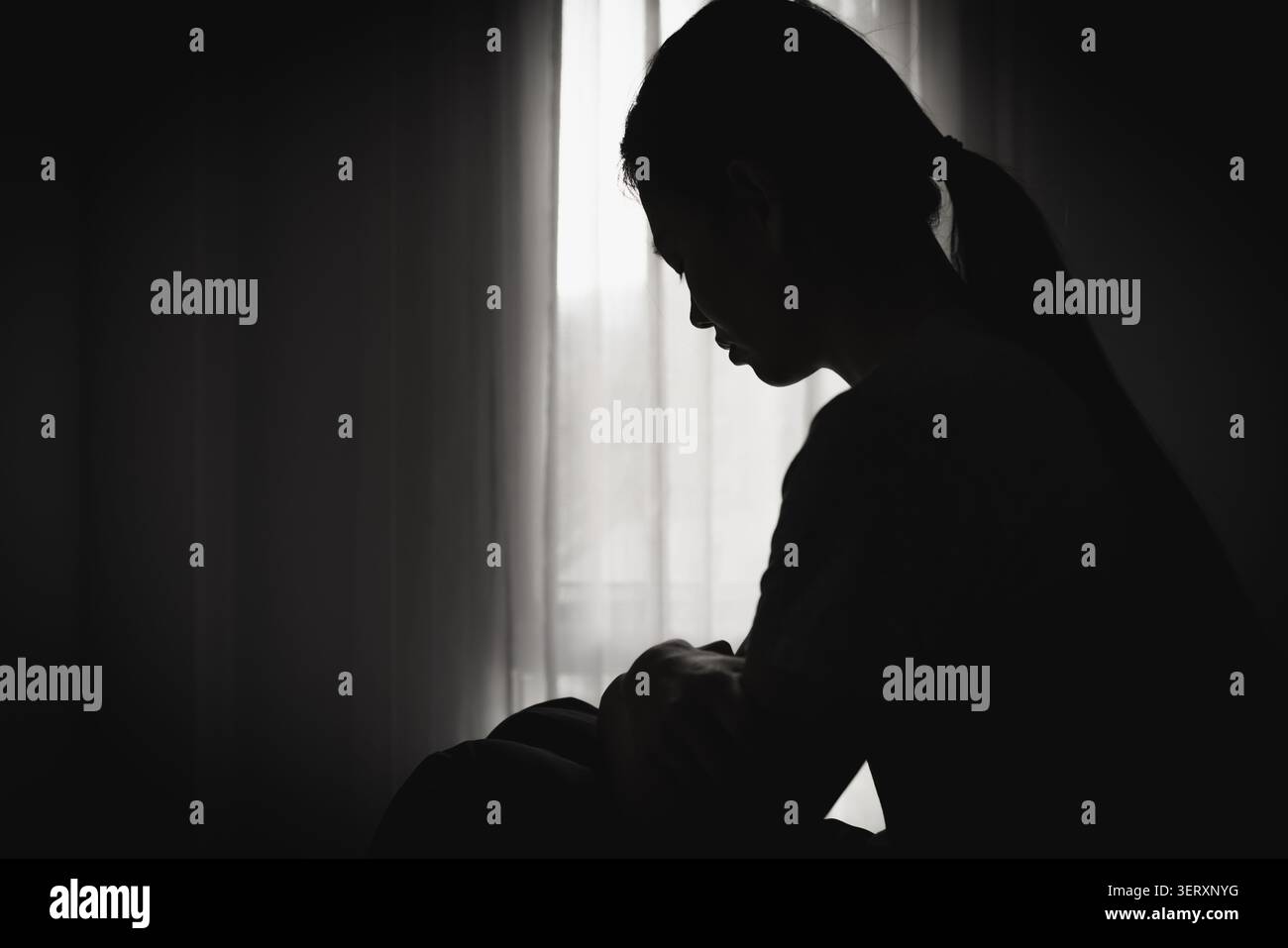 Una donna solitaria seduta in silenzio riflette depressione, dolore emotivo, disperazione e l'impatto psicologico duraturo della violenza contro le donne. Foto Stock