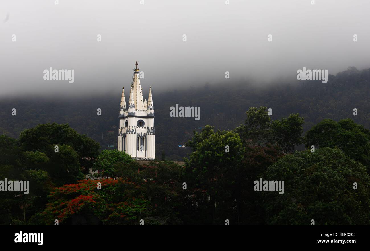 Chiesa di Sant'Anna, Virajpet, Kodagu, Karnataka, che si erge sopra una vegetazione lussureggiante e colline coperte di nebbia, mostrando architettura gotica, fede, eredità. Foto Stock