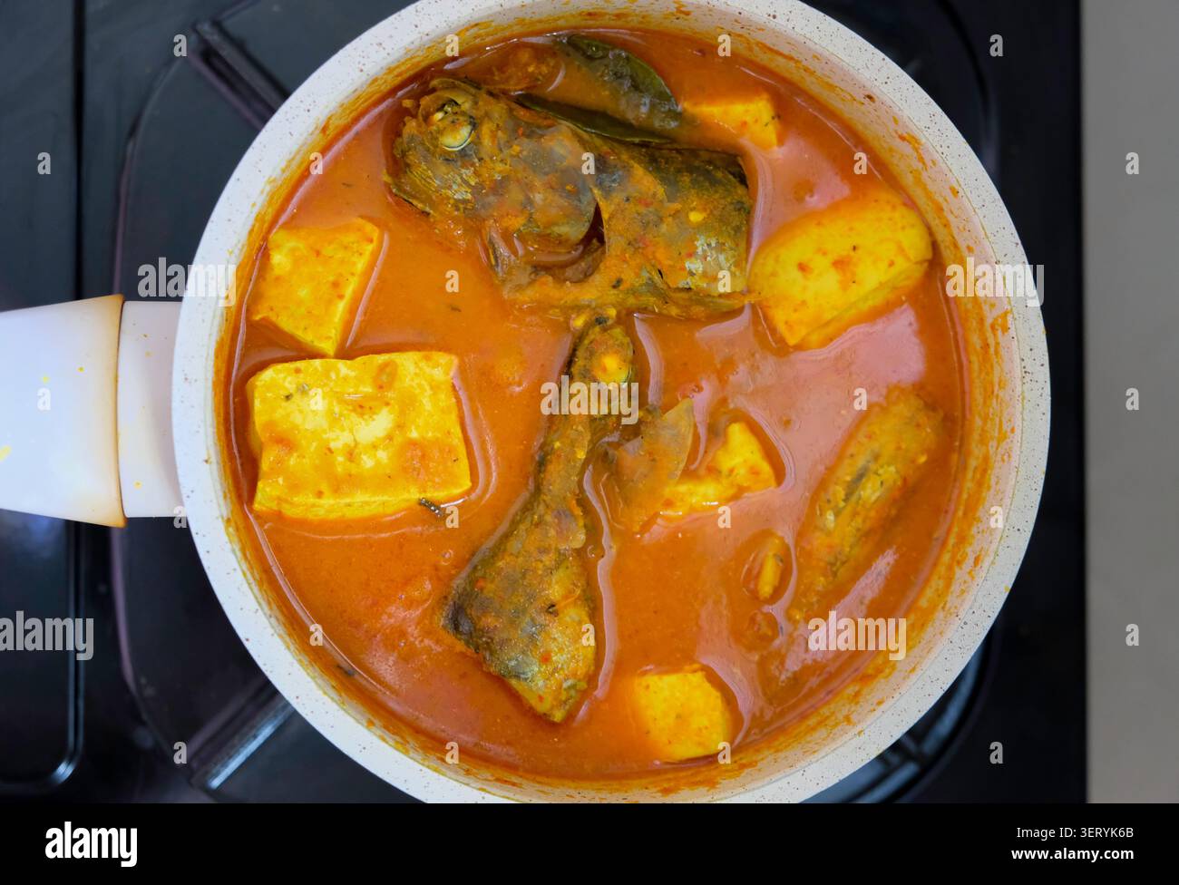 Vista dall'alto del pesce asam pedas e dello stufato di tofu cucinato in una padella su un piano cottura Foto Stock