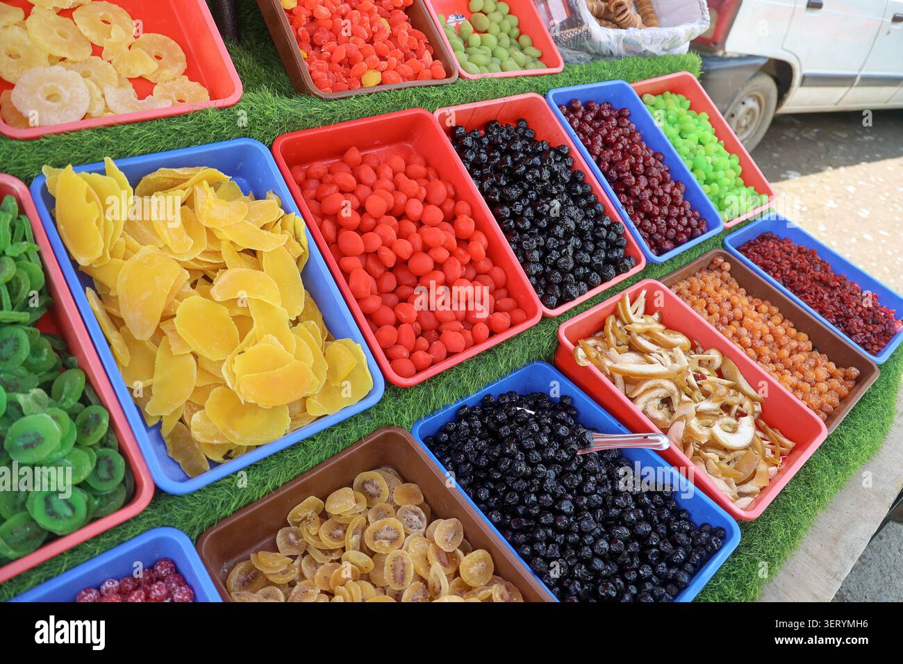 Vista laterale delle fette assortite di albicocche secche, mirtilli e mele esposte in vassoi colorati in un mercato locale nel Kashmir, India. Foto Stock