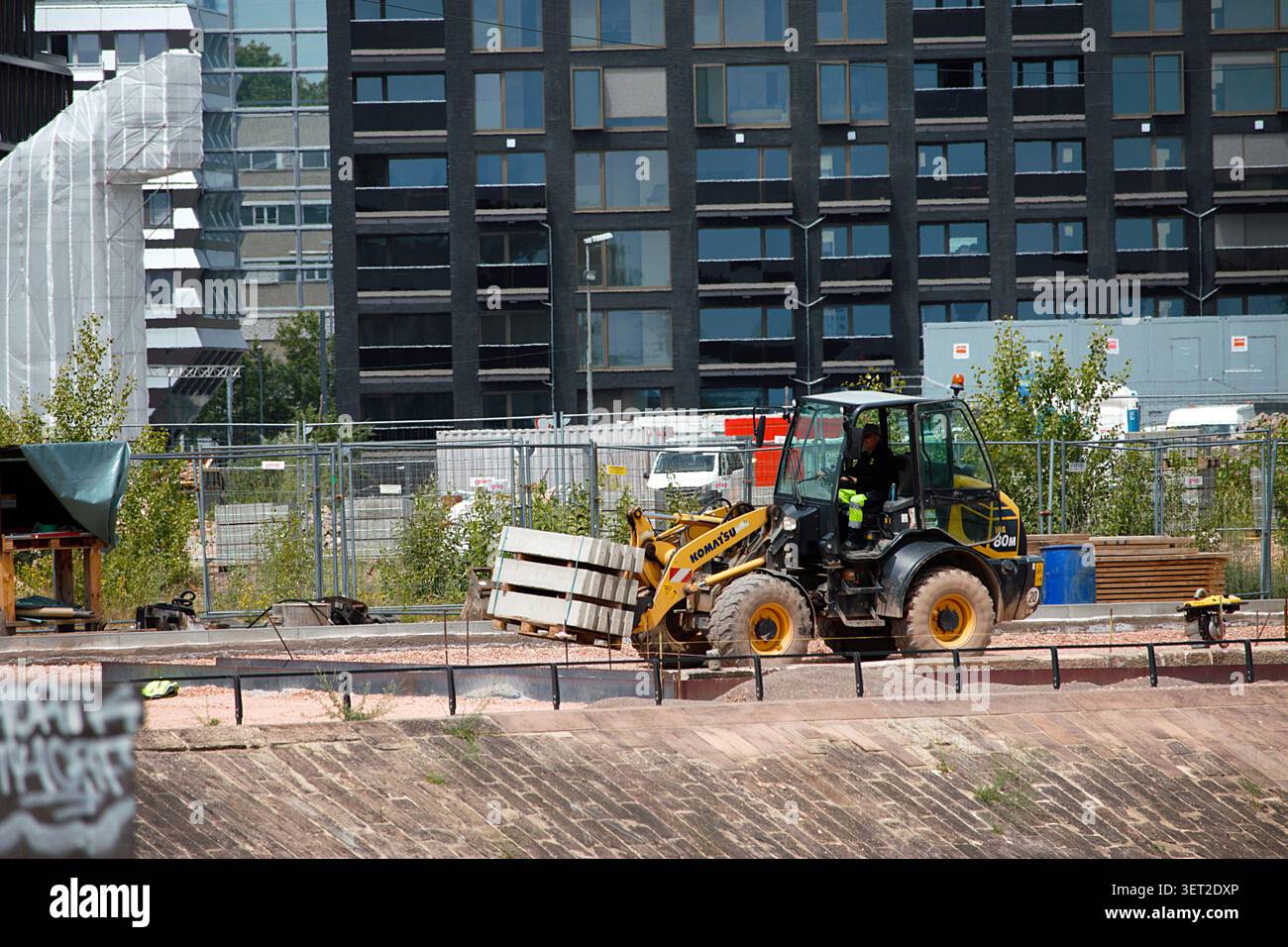 MAINZ, RENANIA-PALATINATO, GERMANIA - 15 GIUGNO 2026: Operaio edile che gestisce un caricatore frontale in un cantiere nel porto di Zollhafen a Mainz. Foto Stock
