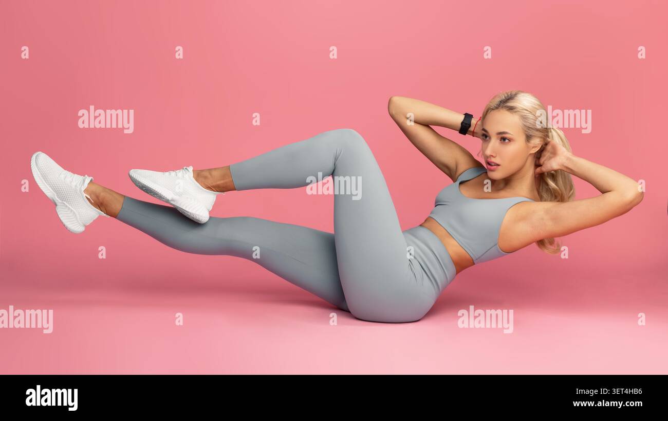 Fit Young Woman che si allenano a pavimento, leggings grigie, sfondo rosa, fitness concept Foto Stock